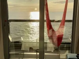 Sunset over the ocean from a Sea Terrace balcony hammock on Brilliant Lady