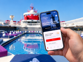 Holding the Virgin Voyages app on a phone by the pool on a Virgin Voyages ship