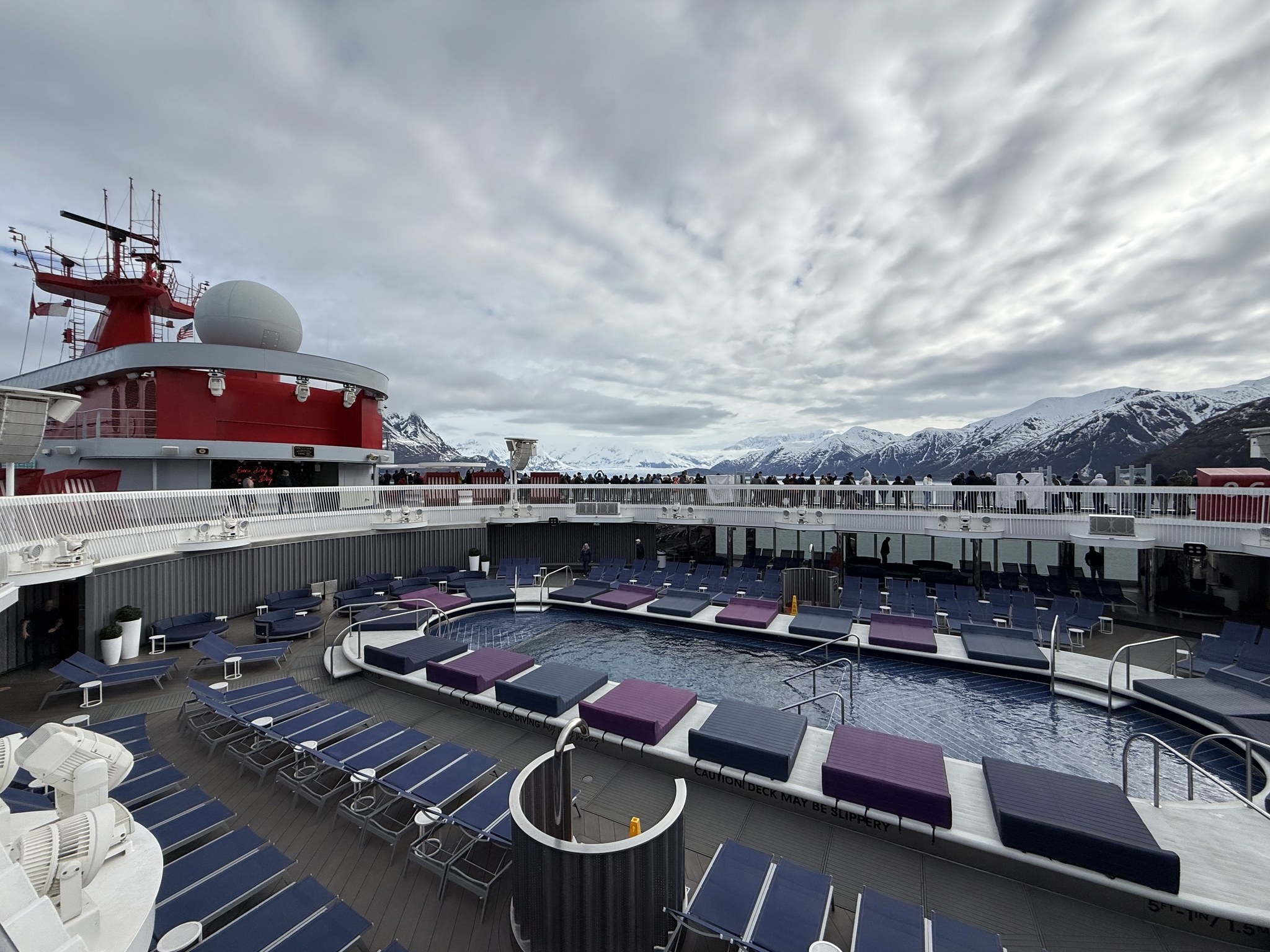 Brilliant Lady’s pool deck under dramatic skies with Alaska mountains on the horizon