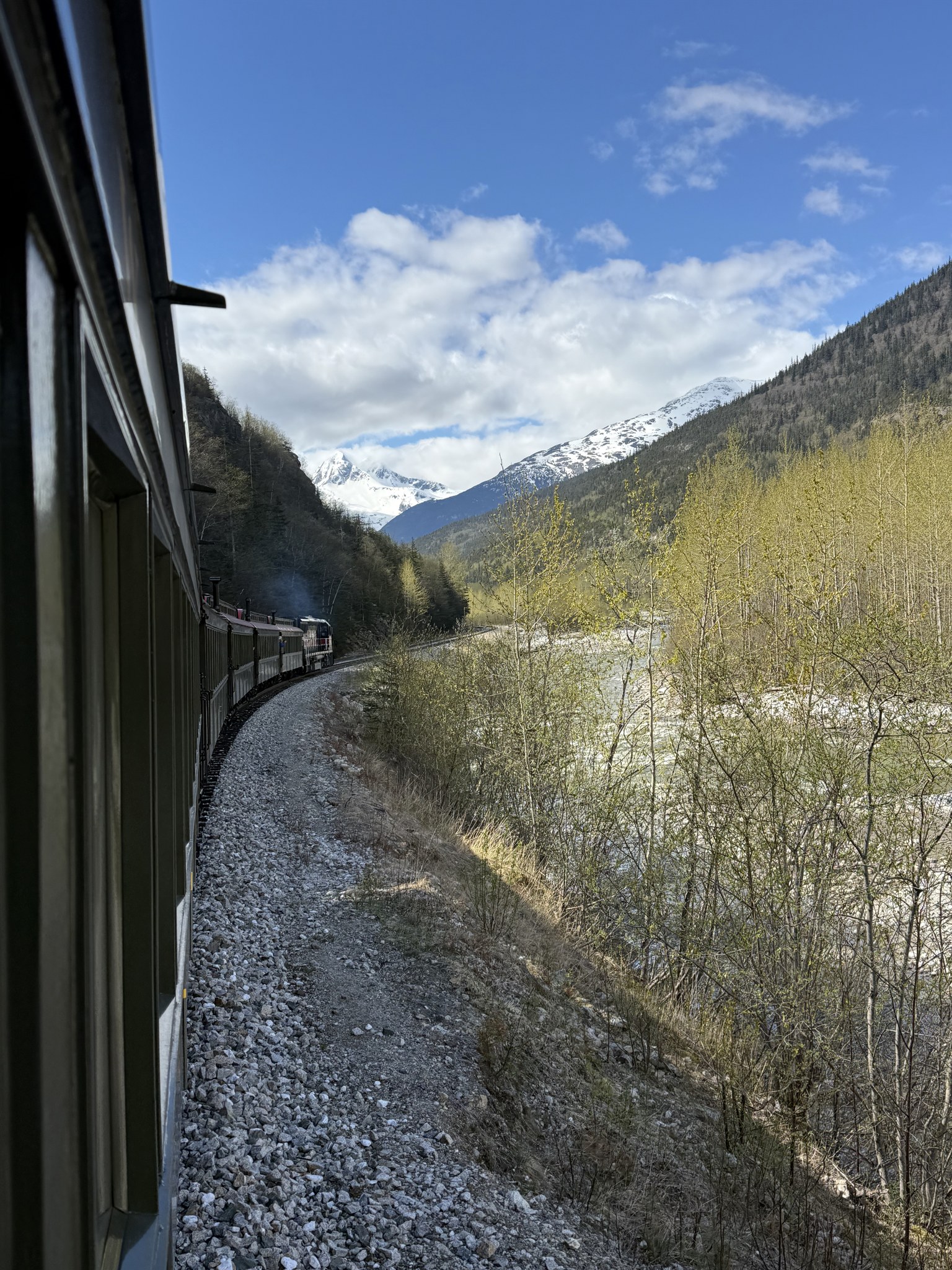 White Pass train winding down the valley towards Skagway with snowy peaks behind