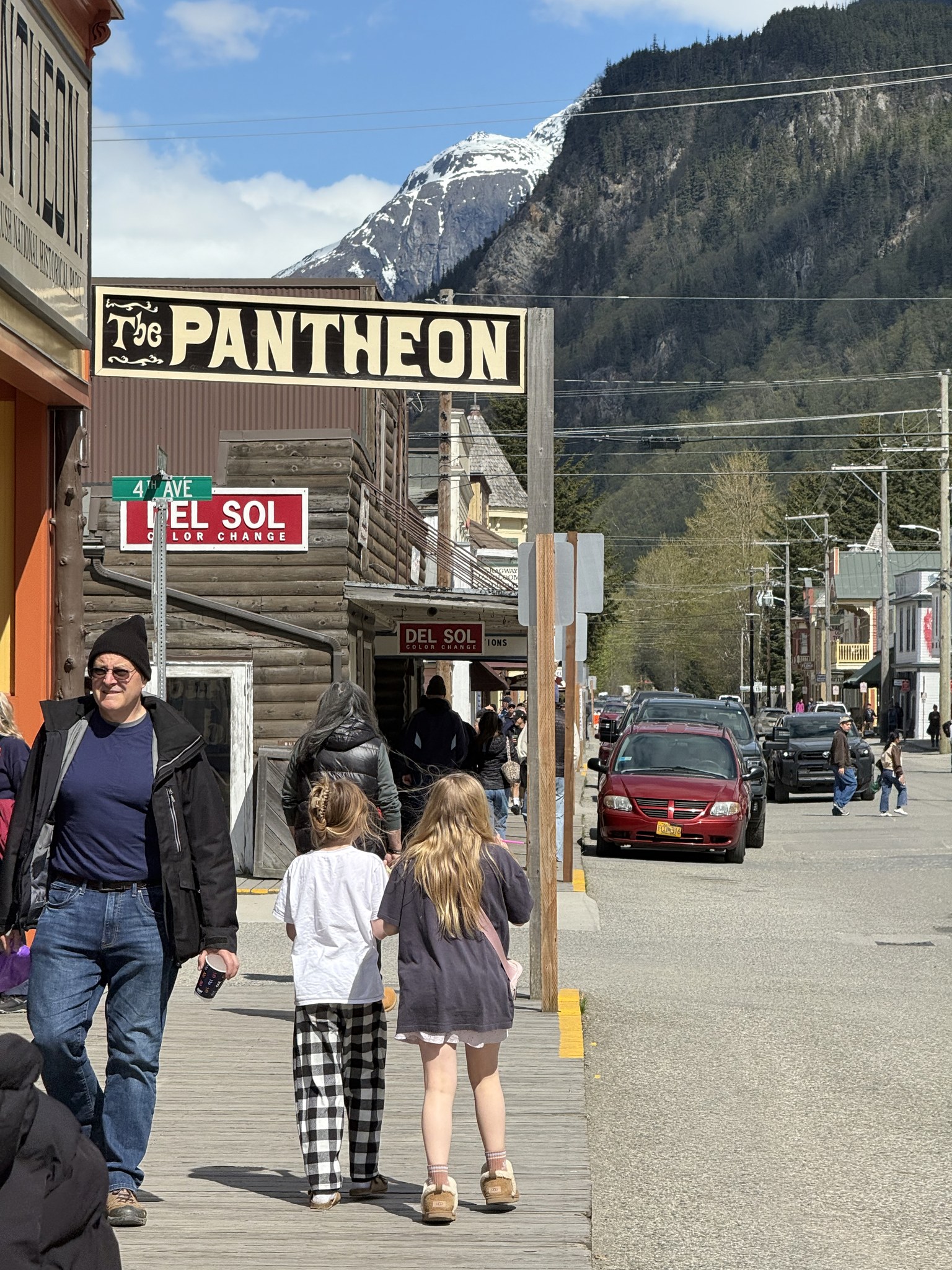 Shoppers on a side street in Skagway with forested mountains behind