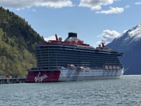 Virgin Voyages Brilliant Lady docked in Alaska beneath snow-capped mountains