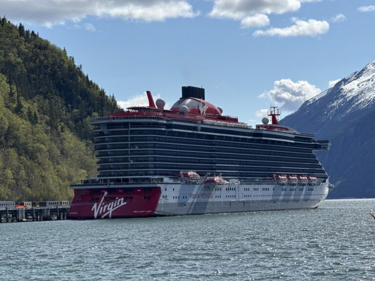 Virgin Voyages Brilliant Lady docked in Alaska beneath snow-capped mountains