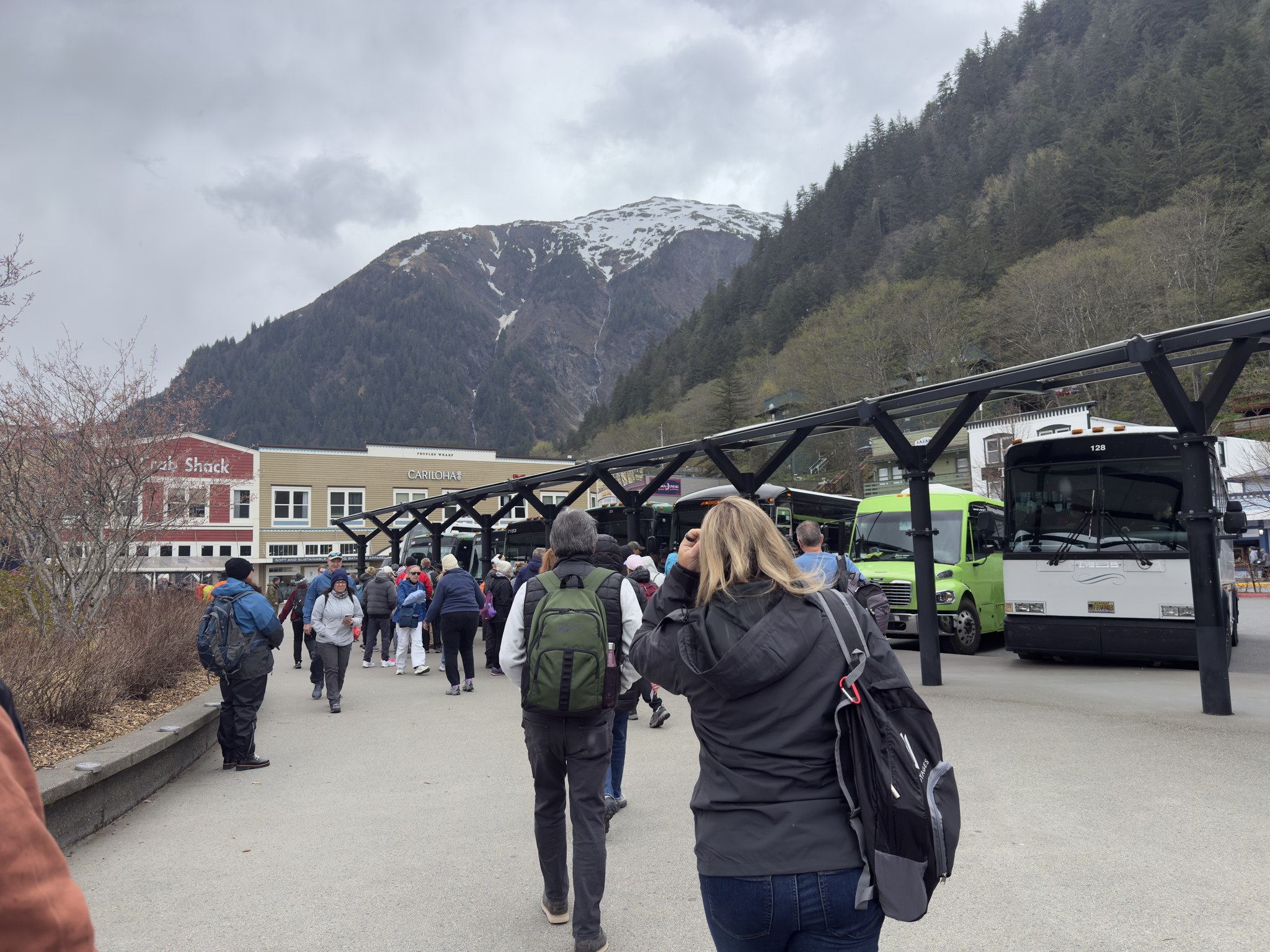Cruise passengers walking along the Juneau waterfront past tour buses