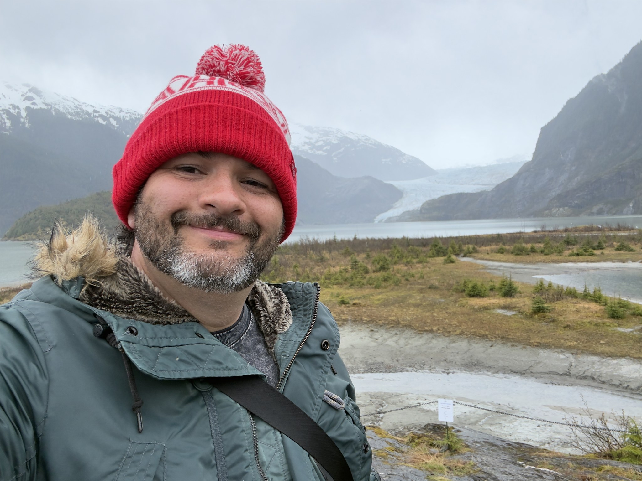 Kieran in a red hat in front of Mendenhall Glacier, Juneau