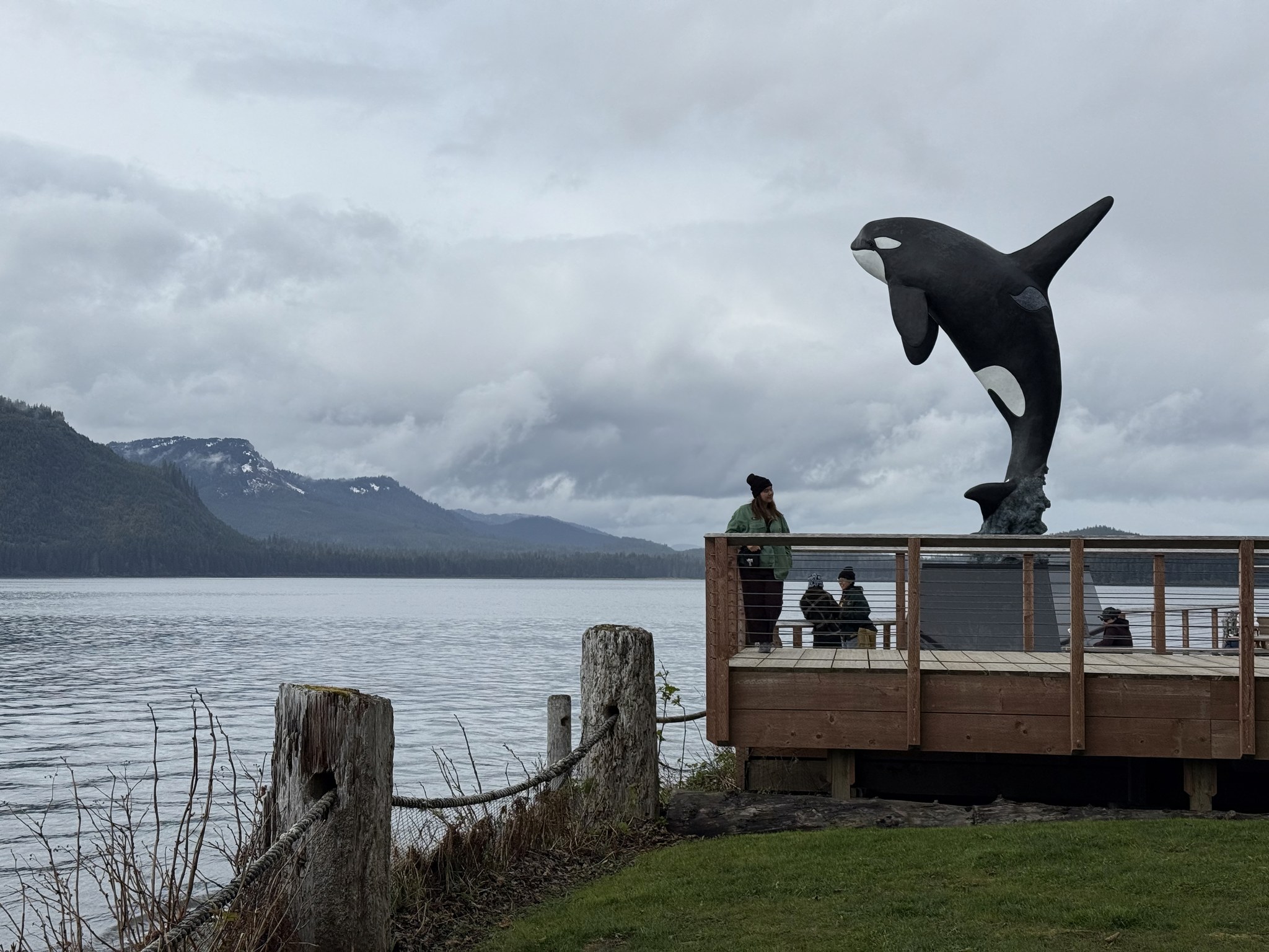 Bronze orca statue on the waterfront at Icy Strait Point with mountains behind