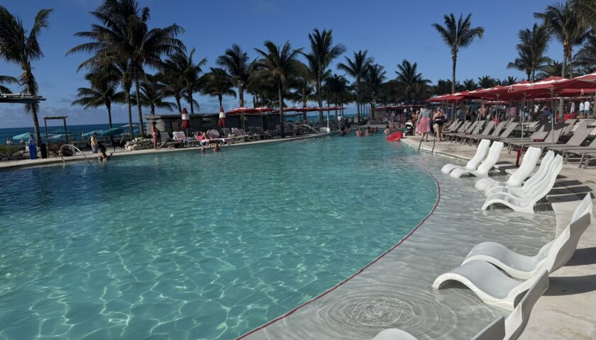 The pool at the Beach Club at Bimini with palm trees and red umbrellas