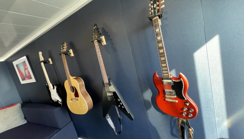 Guitars on the wall of the music room in a Virgin Voyages Massive Suite