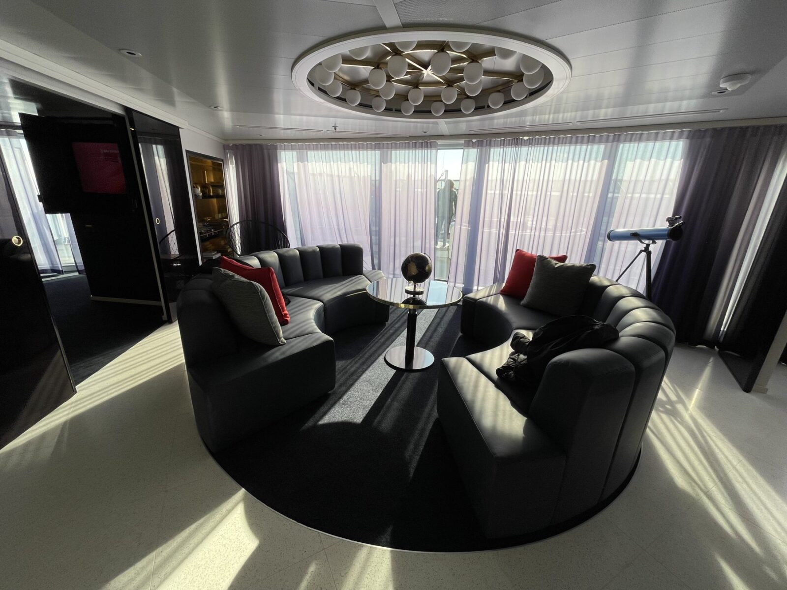 Living room with a curved sofa in a Mega RockStar suite on Virgin Voyages