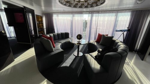 Living room with a curved sofa in a Mega RockStar suite on Virgin Voyages