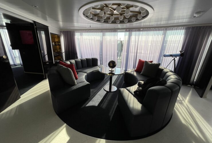 Living room with a curved sofa in a Mega RockStar suite on Virgin Voyages